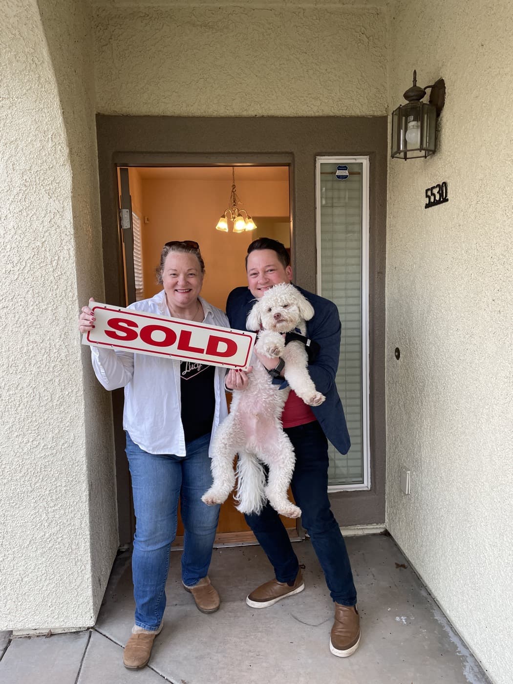 Clients and their dog celebrating with a SOLD sign after closing with Scott Sweeney