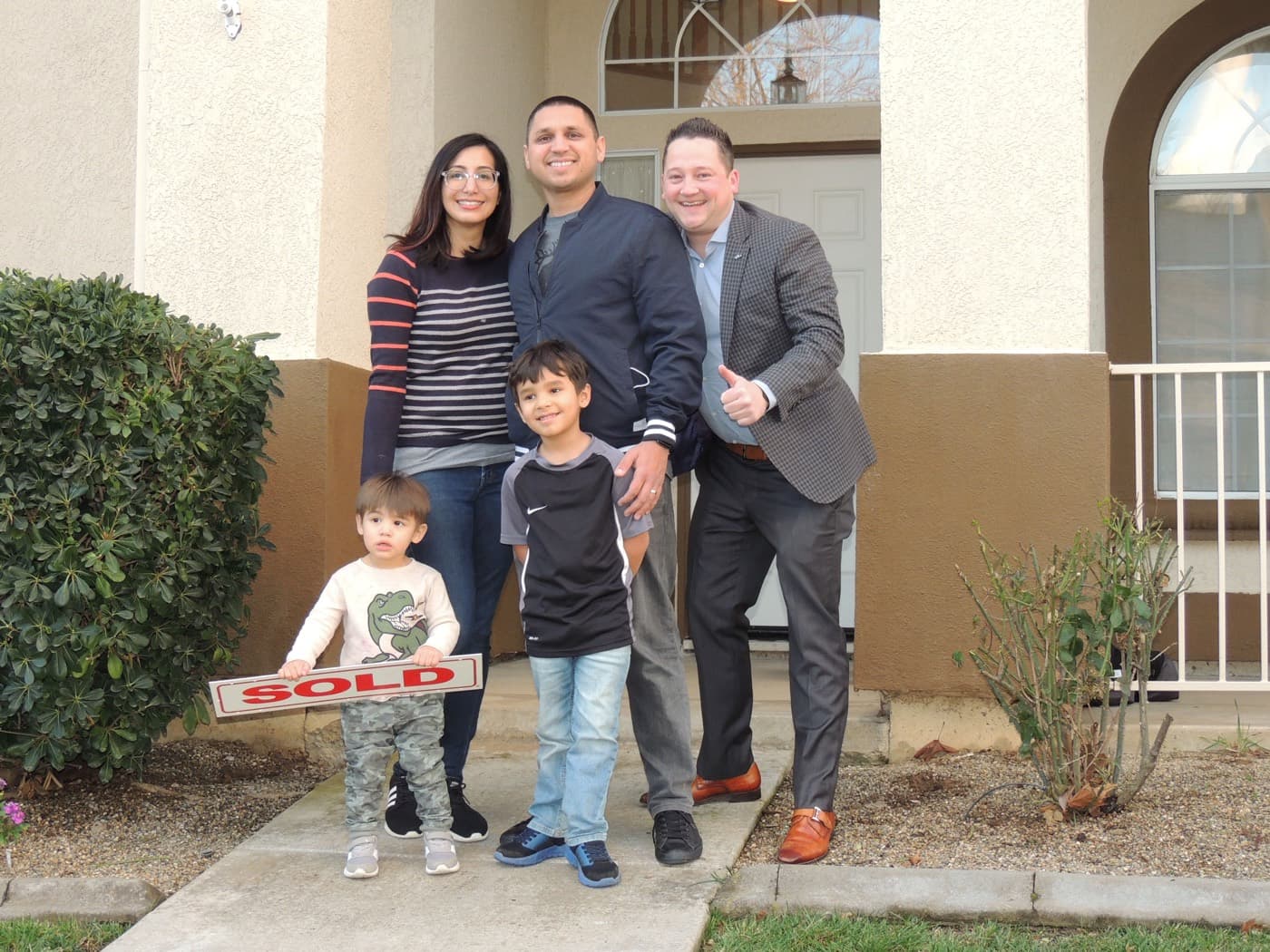 First time homebuyer family with their kids and a SOLD sign in Galt, California