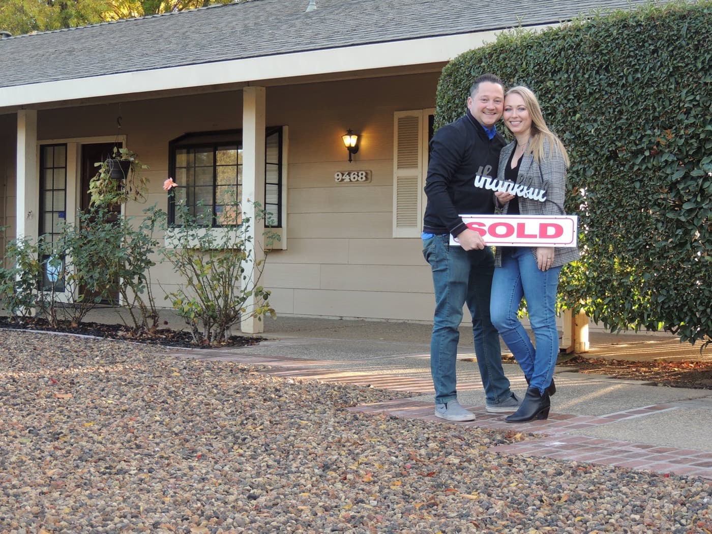Happy sellers with a SOLD sign after closing with Scott Sweeney